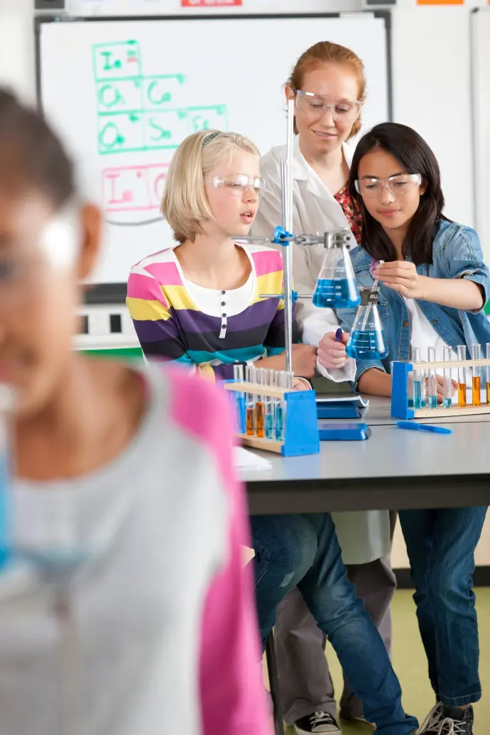 A teacher helps students conduct an experiment in a school chemistry lab.